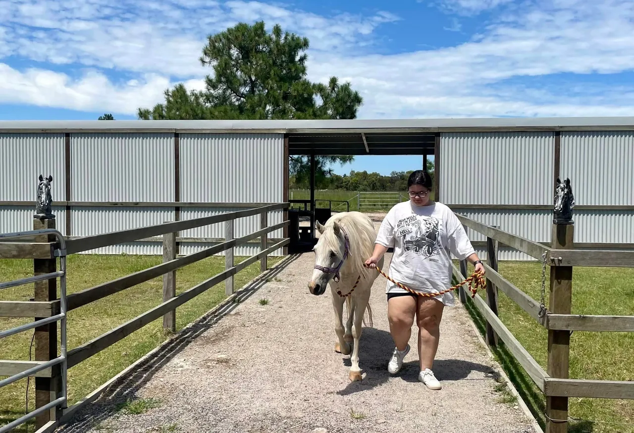 Woman leads horse outside stable